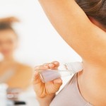 Closeup on woman applying roller deodorant on underarm