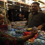 A woman looks at a set of glass bangles before buying them from a stall in a market place, ahead of Eid al-Fitr celebrations, in Lahore